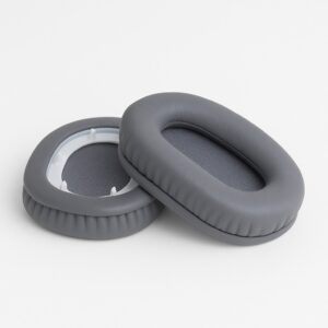 Two gray oval headphone ear pads, one resting on its side showing the inner mesh, the other lying flat displaying the back plastic rim, both on a white background.